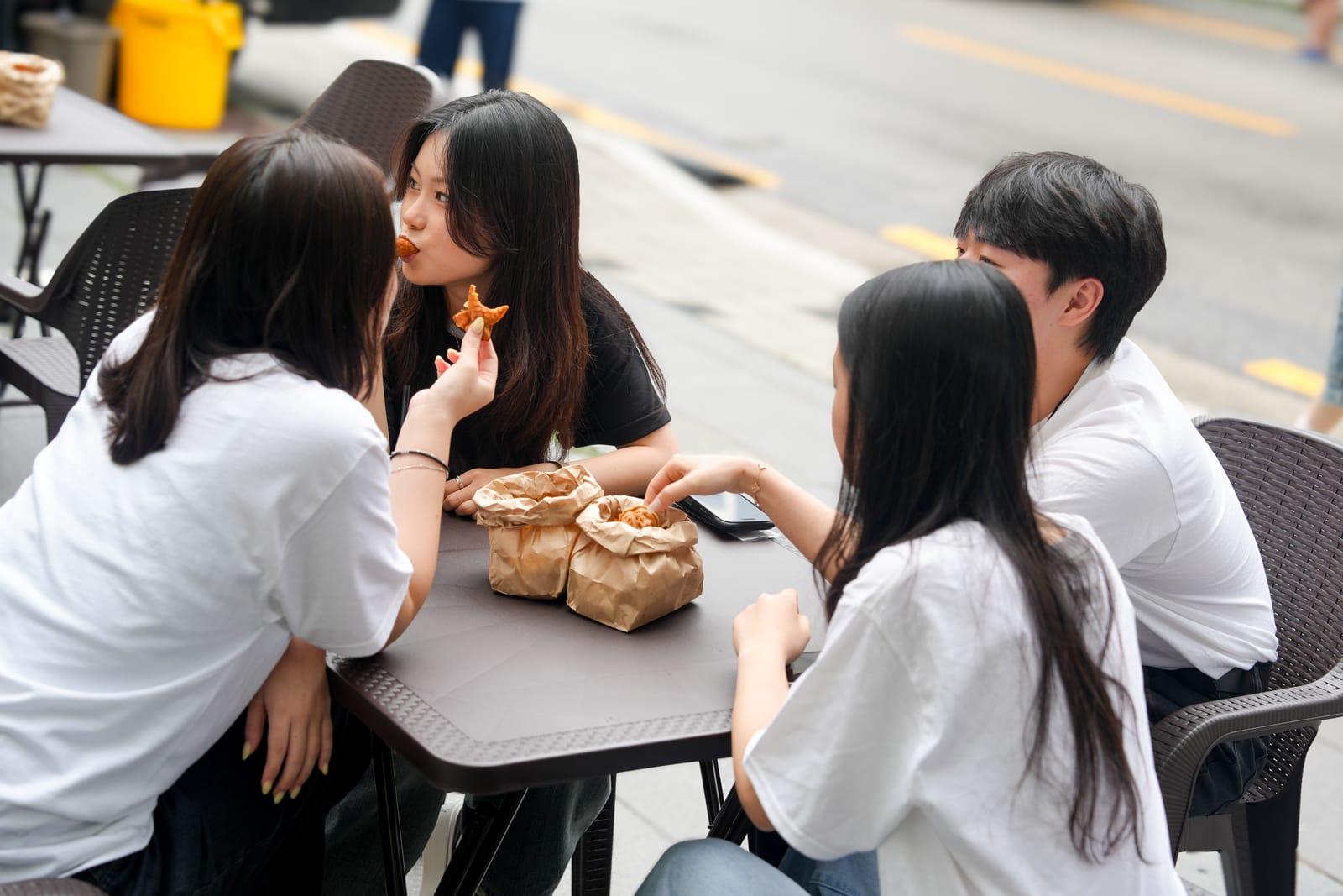 야외 테이블에 둘러앉아 간식을 나누는 참가 학생들
